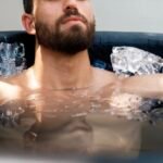 Man doing a cold plunge in an inflatable ice bath to support BJJ recovery and reduce inflammation.