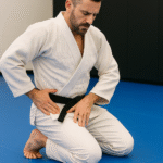 BJJ Injury Prevention Hip Check on the Mats BJJ athlete in a white gi checking his hip during injury-prevention training on the mats